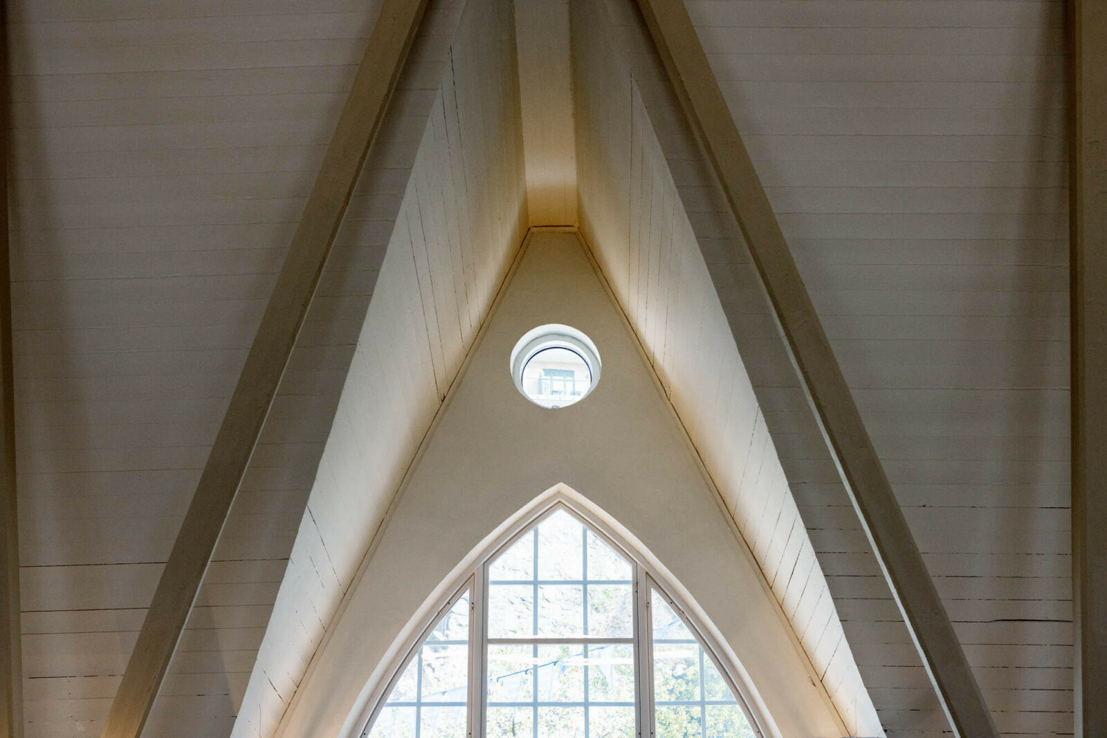 På insidan av hus där man se ett litet runt fönster ovanför ett stort spetsbågigt fönster.