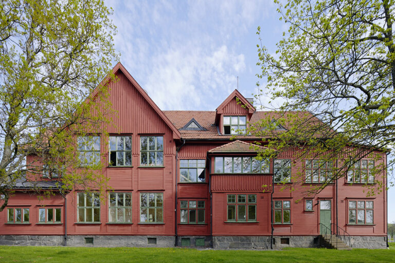 Röd trävilla från sekelskiftet 1900 med grönmålade fönster.